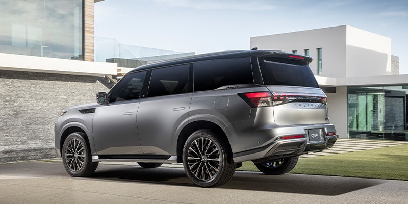 Rear and side view of a silver luxury INFINITI QX80 parked outdoors.