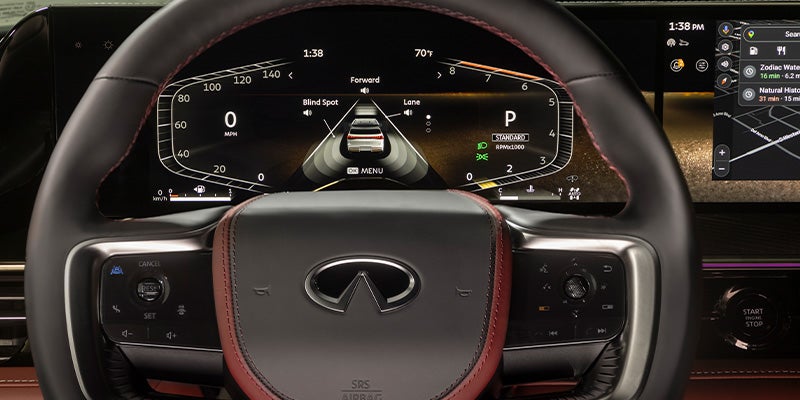Close-up of a car's dashboard and steering wheel, displaying various controls and digital screens.