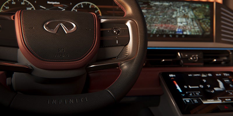 Steering wheel and part of the dashboard with an infotainment screen in a luxury car.